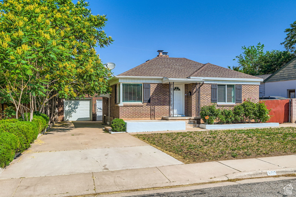 Bungalow featuring brick siding, driveway, a garage, and an outbuilding