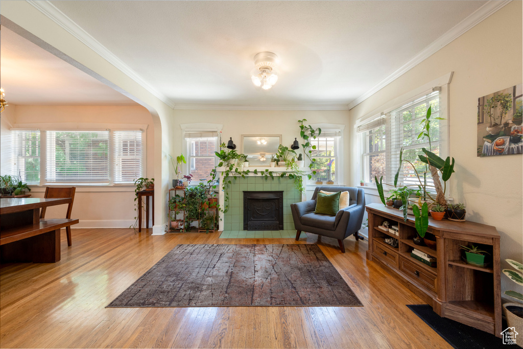 Living room with a tile fireplace, wood finished floors, crown molding, and a chandelier