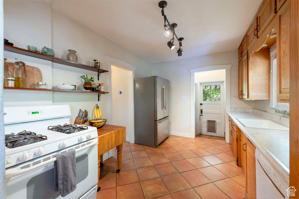 Kitchen with white appliances, light countertops, light tile patterned flooring, brown cabinets, and open shelves