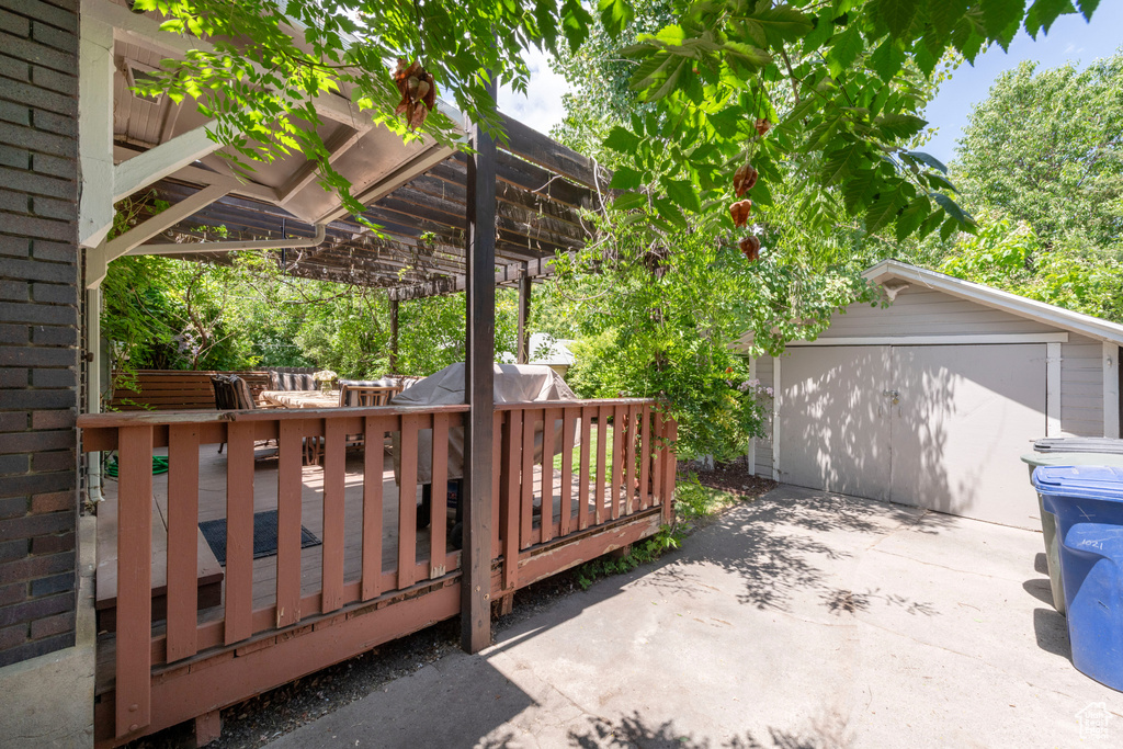 Wooden deck featuring an outbuilding, driveway, and a pergola