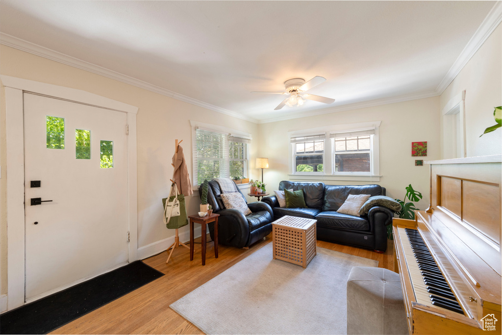Living room with ornamental molding, wood finished floors, and ceiling fan