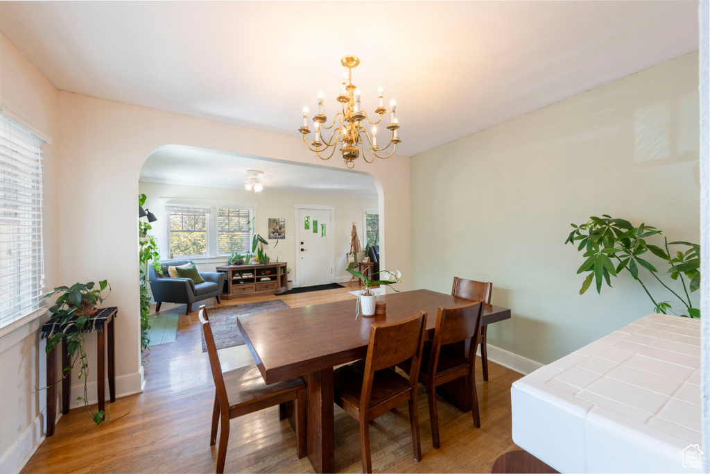 Dining area with arched walkways, light wood-style flooring, and a chandelier