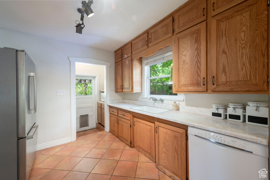 Kitchen featuring freestanding refrigerator, dishwasher, light countertops, and healthy amount of natural light