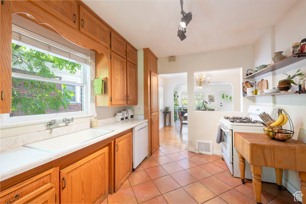 Kitchen with white appliances, light countertops, light tile patterned floors, open shelves, and a chandelier