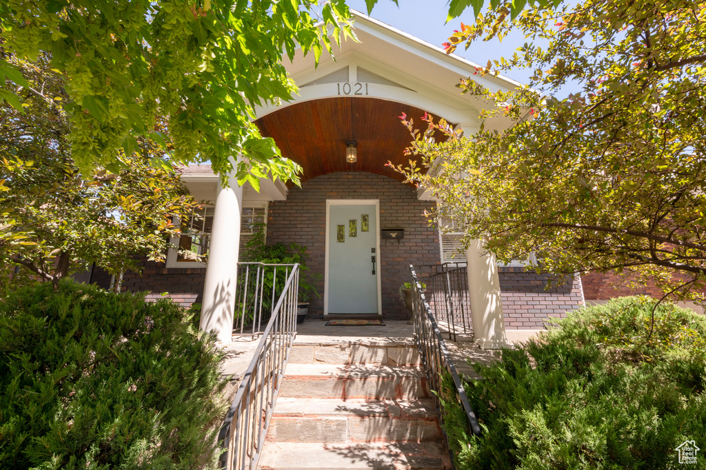 Doorway to property featuring brick siding and covered porch
