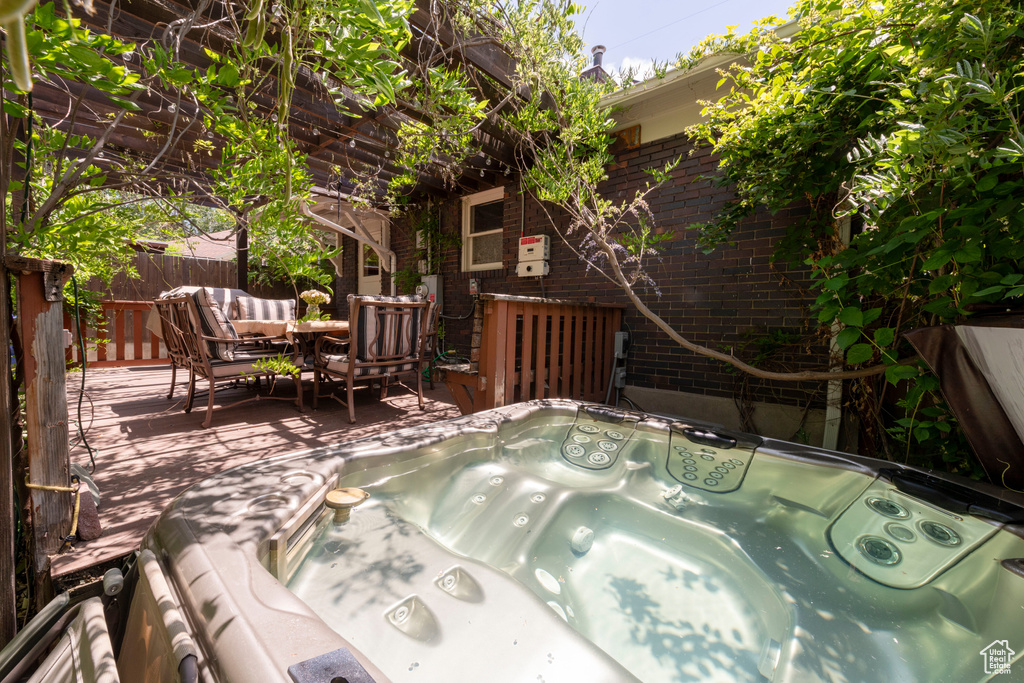 View of patio with a hot tub, a deck, and outdoor dining area