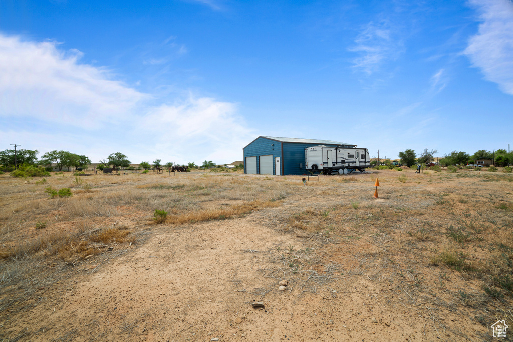 View of yard with a garage, an outbuilding, and a view of rural / pastoral area