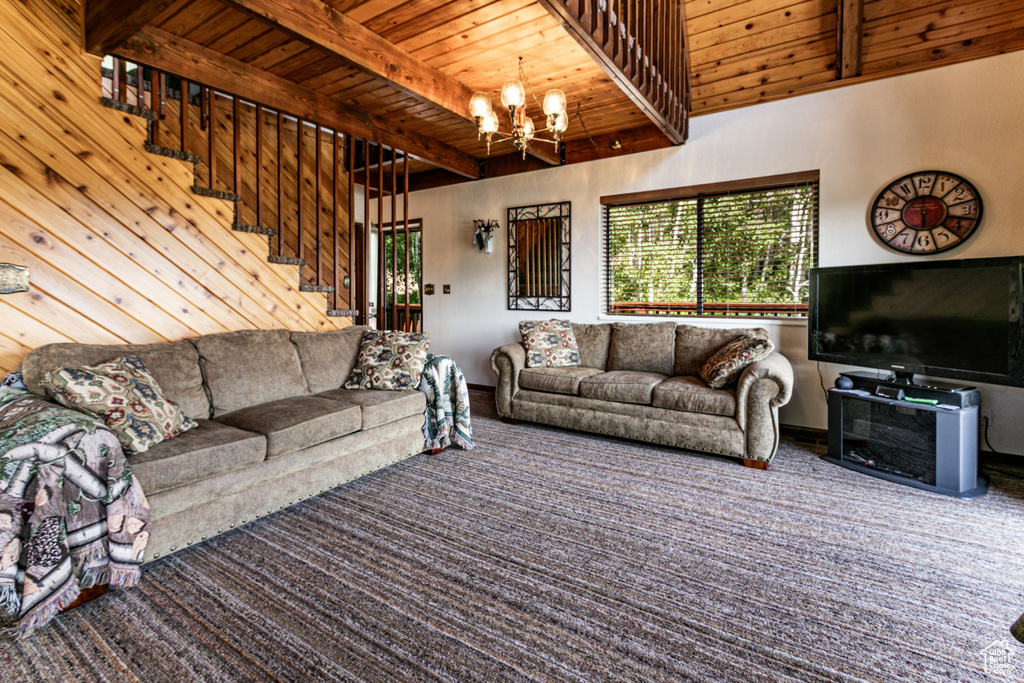 Living area featuring a wood ceiling with exposed beams, a chandelier, stairs, and carpet flooring