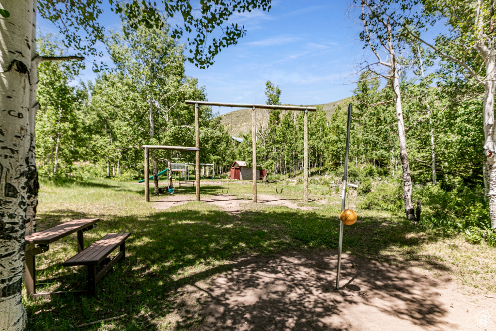 View of jungle gym featuring a shed, a yard, and a mountain view