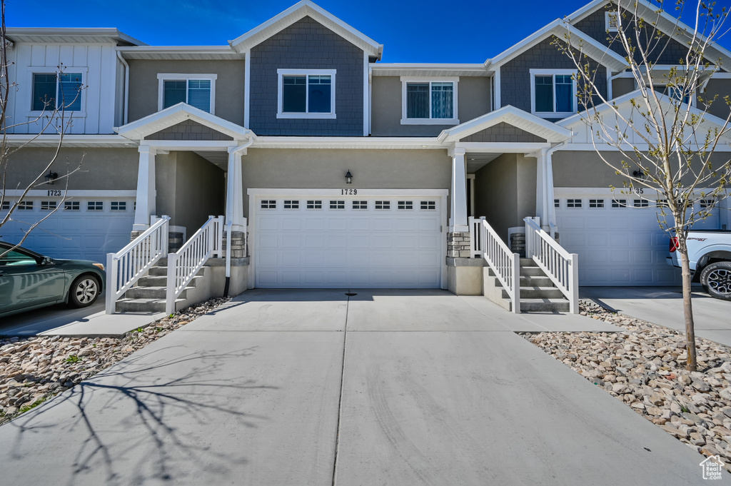 View of front of property with an attached garage, driveway, and stucco siding