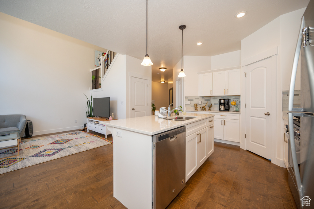 Kitchen with stainless steel dishwasher, dark wood-style floors, white cabinets, backsplash, and recessed lighting