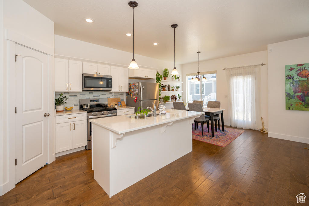 Kitchen with stainless steel appliances, light countertops, white cabinetry, a chandelier, and recessed lighting