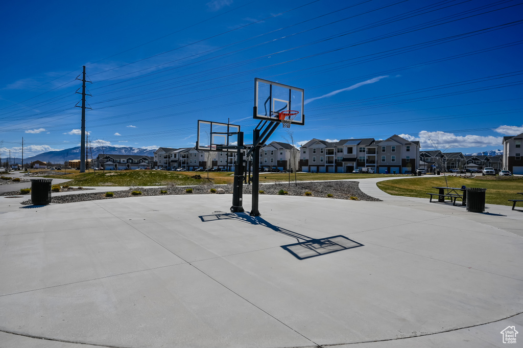 View of basketball court featuring a mountain view, a residential view, basketball hoop, and a yard