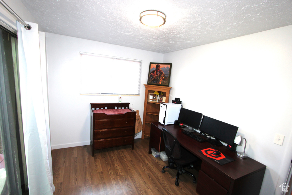 Office area featuring a textured ceiling and dark wood-style flooring