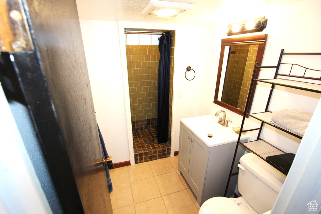 Bathroom with vanity, a tile shower, and tile patterned floors