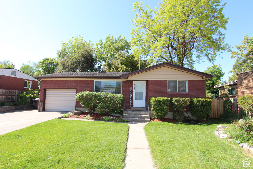 Single story home featuring an attached garage, brick siding, and driveway