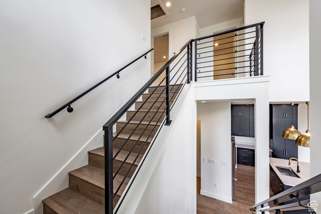 Staircase featuring wood finished floors, a towering ceiling, and recessed lighting