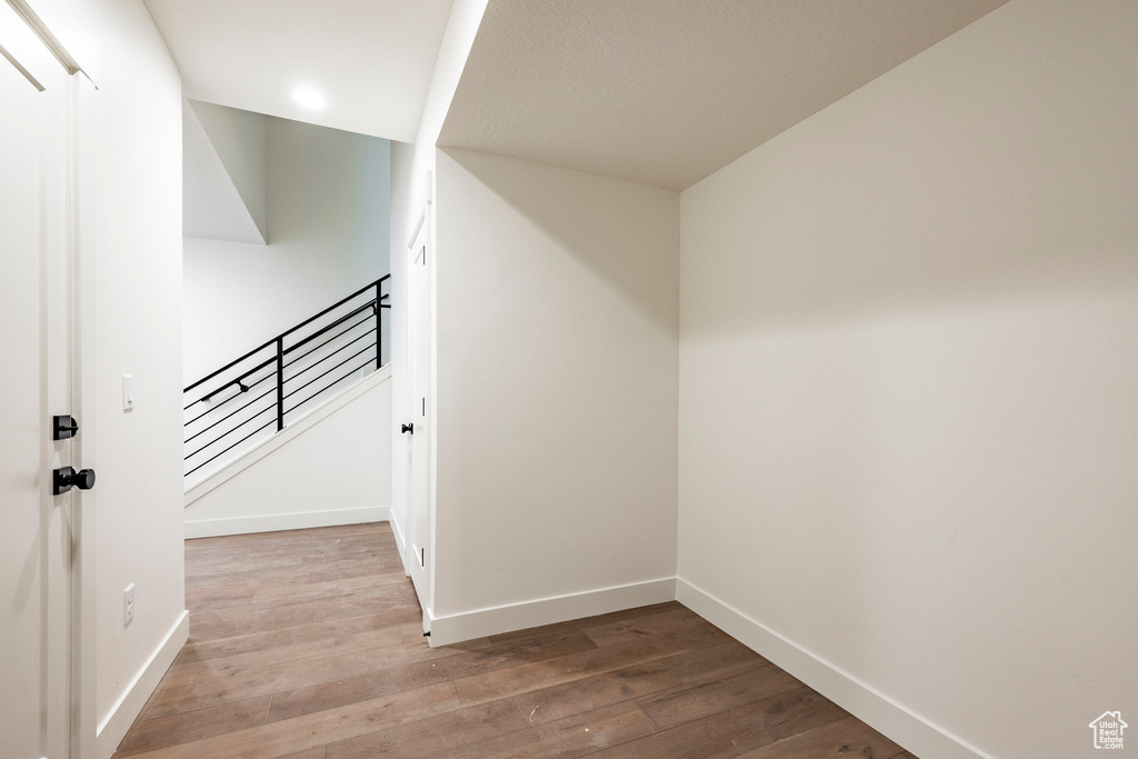 Hallway with wood finished floors, stairs, and recessed lighting