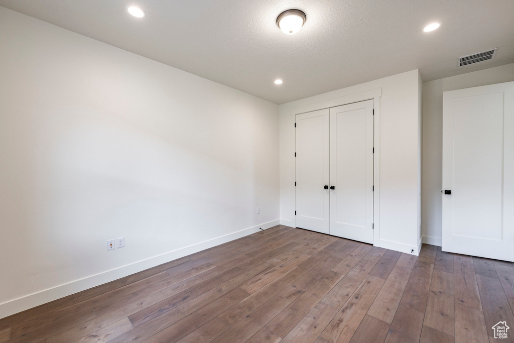 Unfurnished bedroom featuring hardwood / wood-style flooring, recessed lighting, and a closet