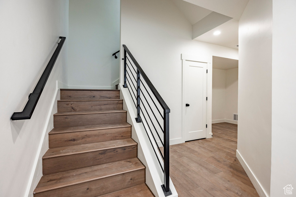 Stairs featuring wood finished floors and recessed lighting