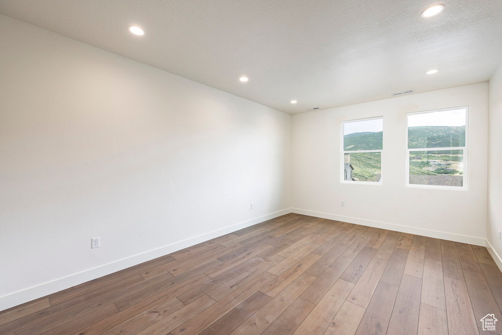 Spare room with hardwood / wood-style floors and recessed lighting