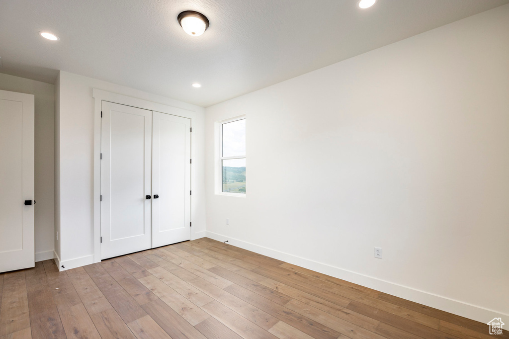 Unfurnished bedroom featuring light wood-type flooring, recessed lighting, and a closet
