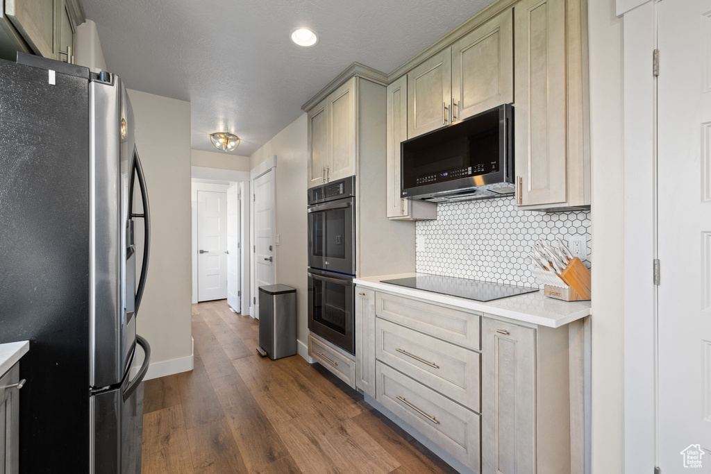 Kitchen featuring black appliances, light countertops, backsplash, dark wood finished floors, and recessed lighting