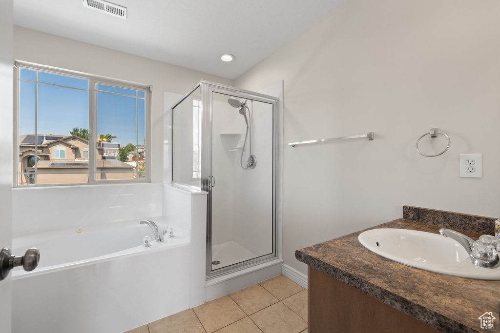 Full bathroom featuring a stall shower, a garden tub, tile patterned flooring, and vanity