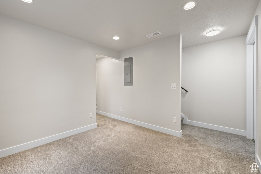 Unfurnished room featuring electric panel, light carpet, and recessed lighting