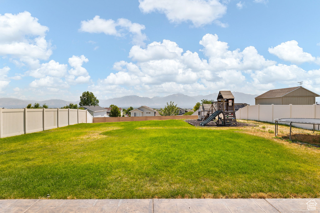 View of yard featuring a playground, a trampoline, and a mountain view