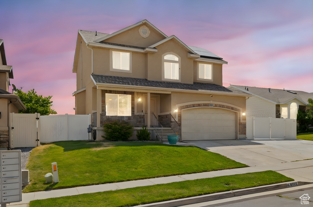 Traditional-style home with a gate, concrete driveway, solar panels, stucco siding, and a garage
