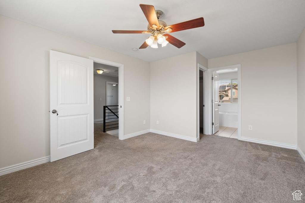 Unfurnished bedroom featuring carpet, ensuite bath, and ceiling fan