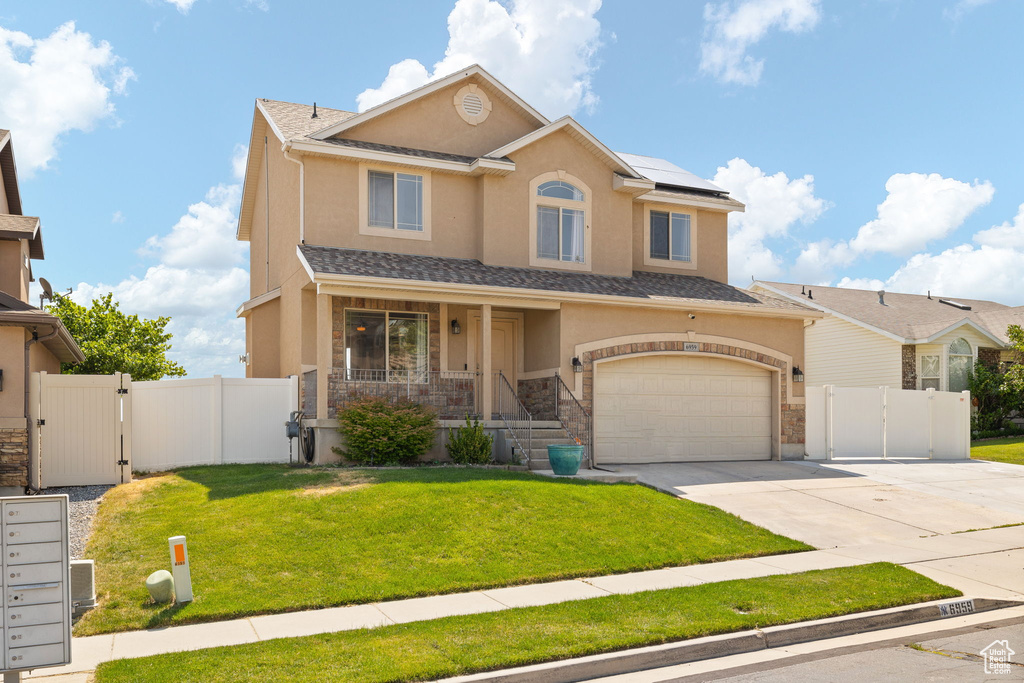 View of front facade with a gate, concrete driveway, a garage, stucco siding, and roof mounted solar panels
