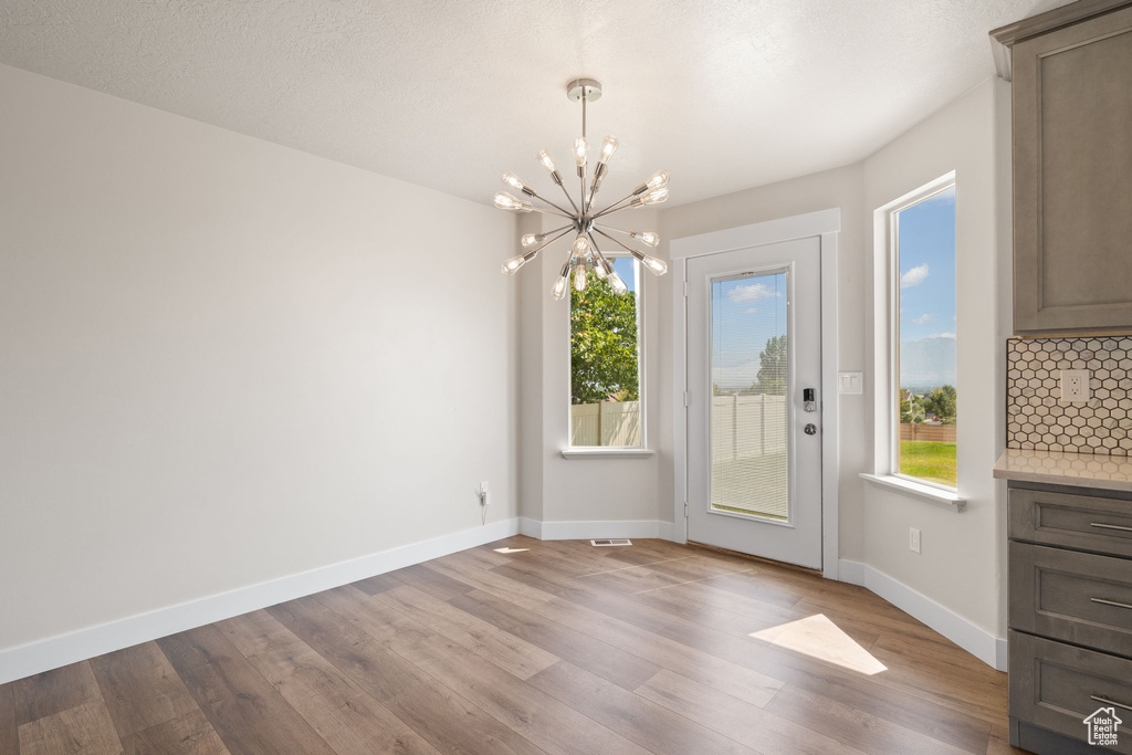 Unfurnished dining area with a chandelier and wood finished floors