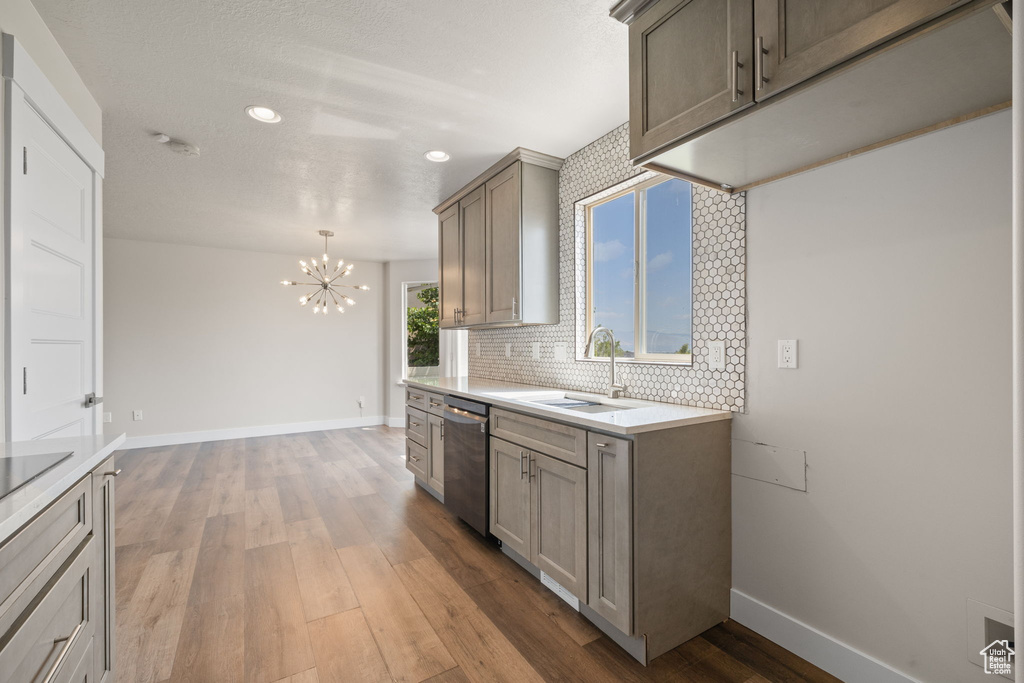 Kitchen with stainless steel dishwasher, a chandelier, light wood-type flooring, recessed lighting, and backsplash