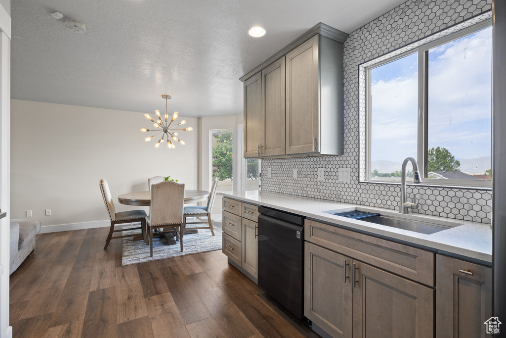 Kitchen featuring dishwasher, a chandelier, light countertops, and tasteful backsplash