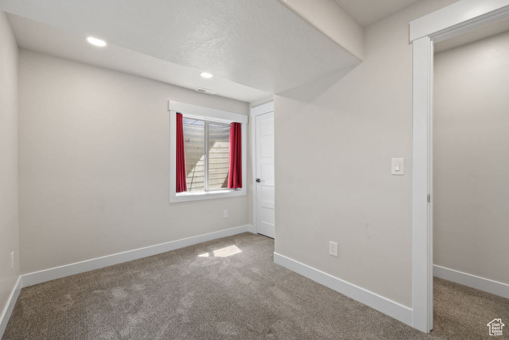 Carpeted spare room with baseboards and recessed lighting