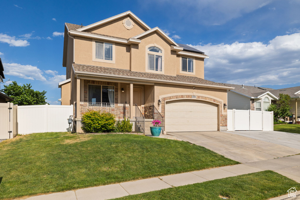 View of front of property with a porch, driveway, roof mounted solar panels, and stucco siding