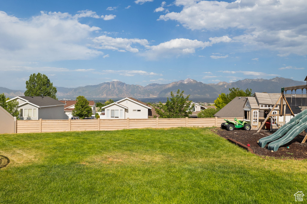 Fenced backyard with a playground, a mountain view, and a residential view