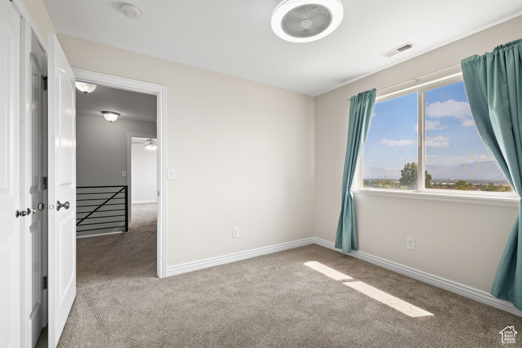 Empty room with carpet flooring and a smoke detector