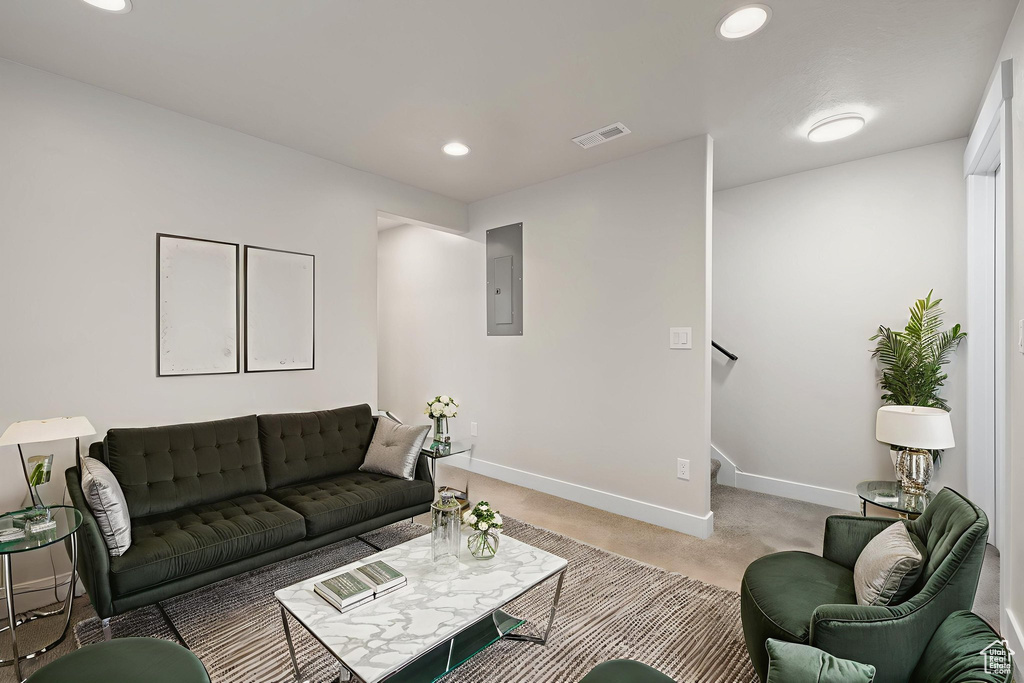 Living area with electric panel, recessed lighting, stairs, and light colored carpet