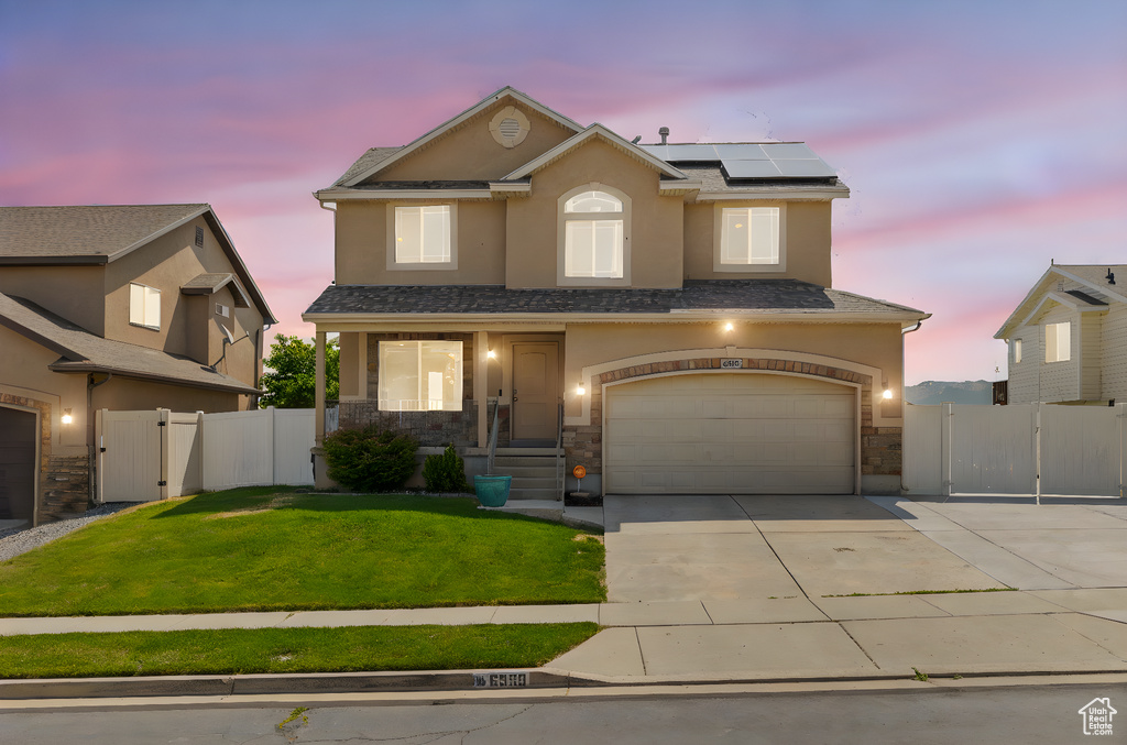 Traditional-style house with a gate, driveway, solar panels, and stucco siding