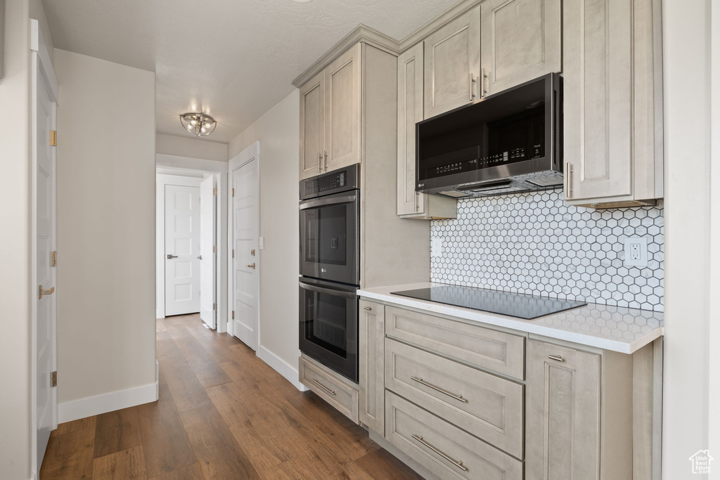 Kitchen featuring appliances with stainless steel finishes, light countertops, dark wood-type flooring, and backsplash