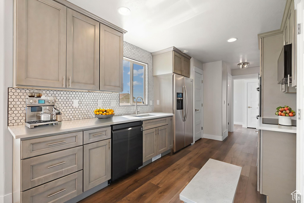 Kitchen featuring appliances with stainless steel finishes, decorative backsplash, dark wood-type flooring, light countertops, and recessed lighting