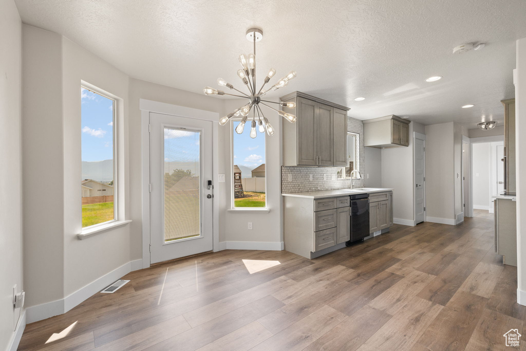 Kitchen featuring gray cabinetry, a chandelier, black dishwasher, decorative backsplash, and recessed lighting
