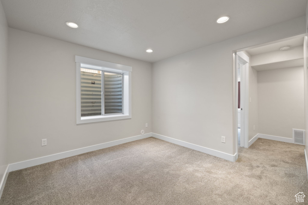 Empty room featuring light colored carpet, recessed lighting, and a smoke detector