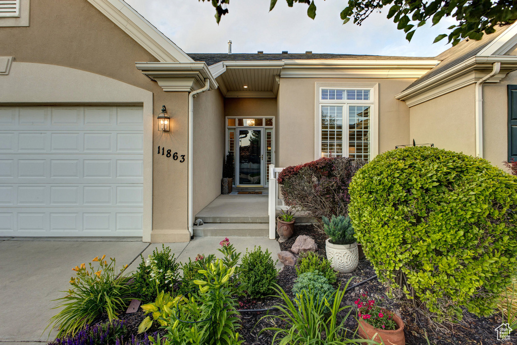 Entrance to property featuring stucco siding, a garage, and concrete driveway