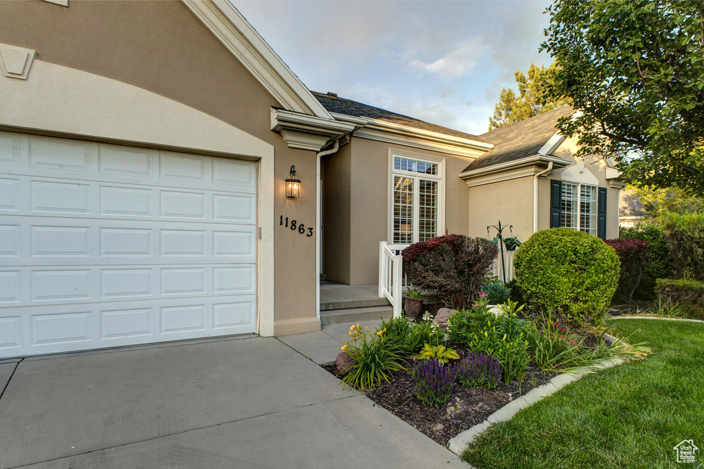 View of exterior entry with stucco siding, driveway, and an attached garage