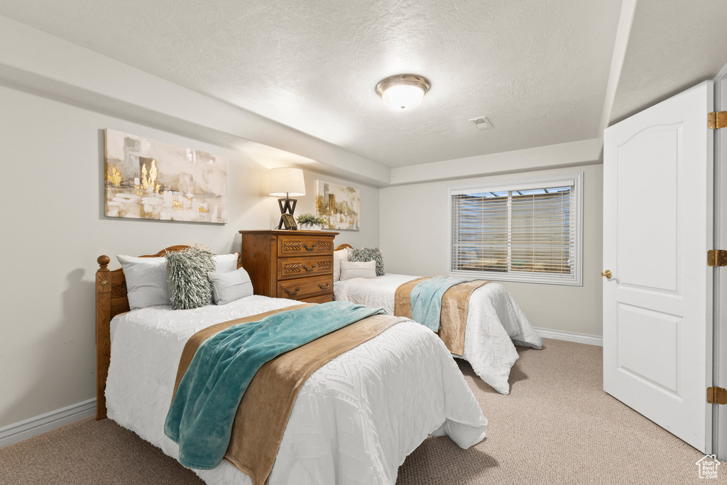 Bedroom with light colored carpet and a textured ceiling