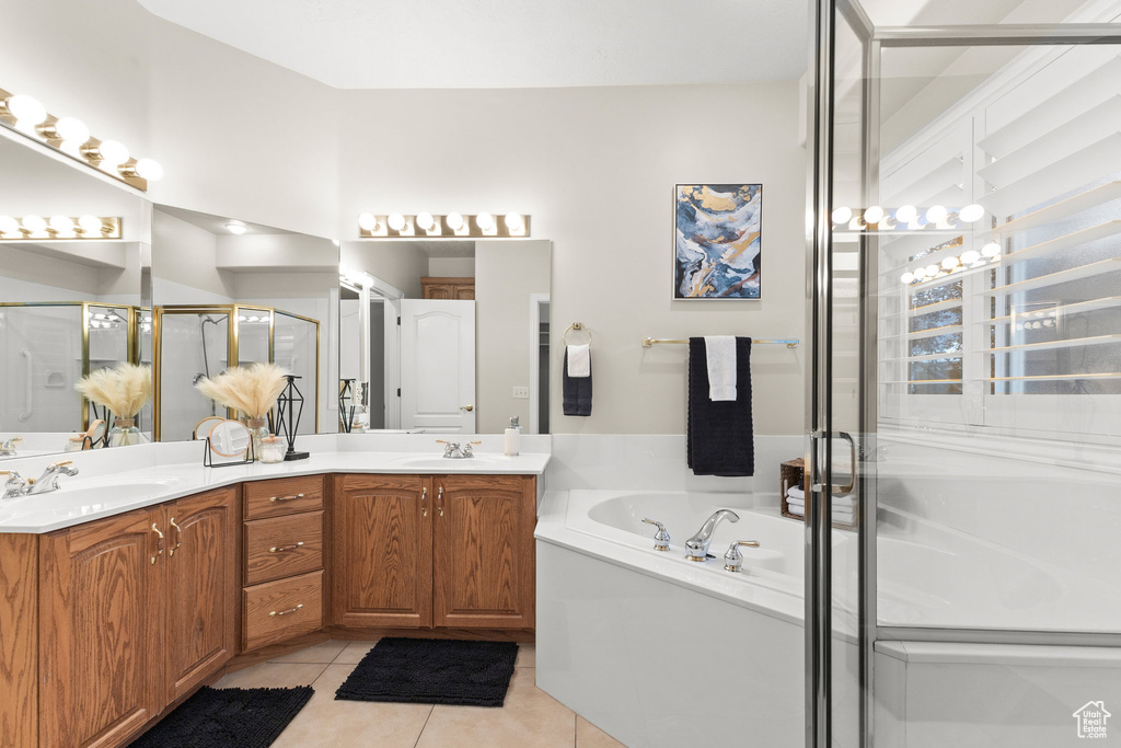 Bathroom featuring a bath, double vanity, a stall shower, and tile patterned floors